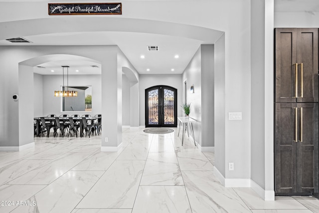 foyer with french doors and a notable chandelier