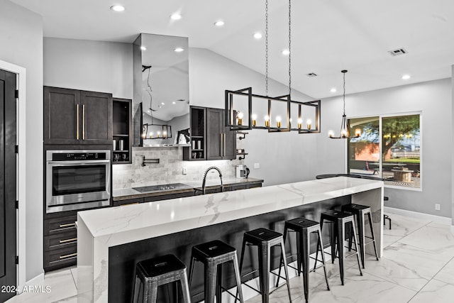 kitchen with lofted ceiling, light stone counters, stainless steel oven, hanging light fixtures, and a spacious island