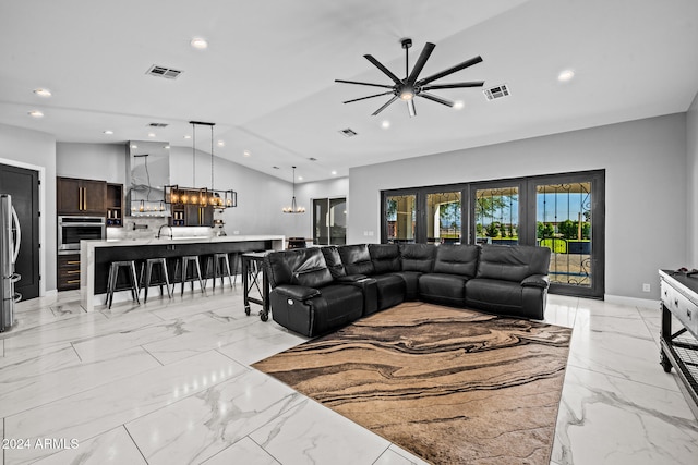 living room with ceiling fan with notable chandelier and lofted ceiling