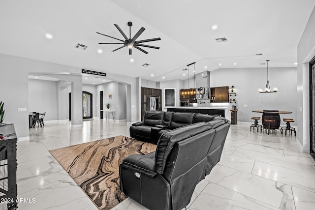 living room featuring ceiling fan with notable chandelier and vaulted ceiling