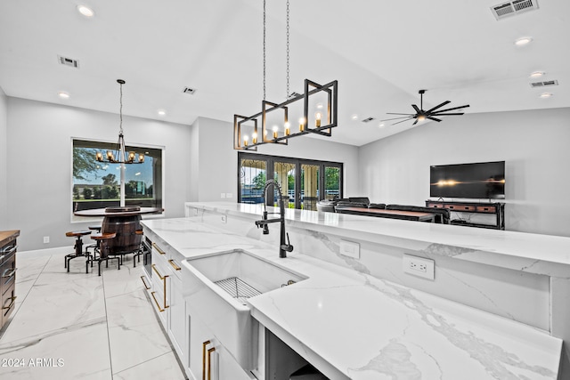 kitchen featuring pendant lighting, light stone counters, plenty of natural light, and sink