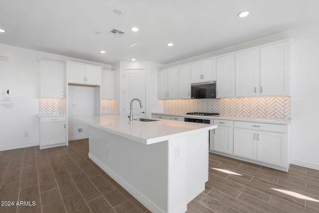 kitchen with dark hardwood / wood-style flooring, sink, stainless steel appliances, and a center island with sink