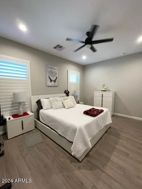 bedroom featuring ceiling fan, multiple windows, and wood-type flooring