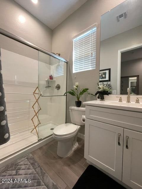 bathroom featuring toilet, vanity, a shower with door, and hardwood / wood-style floors