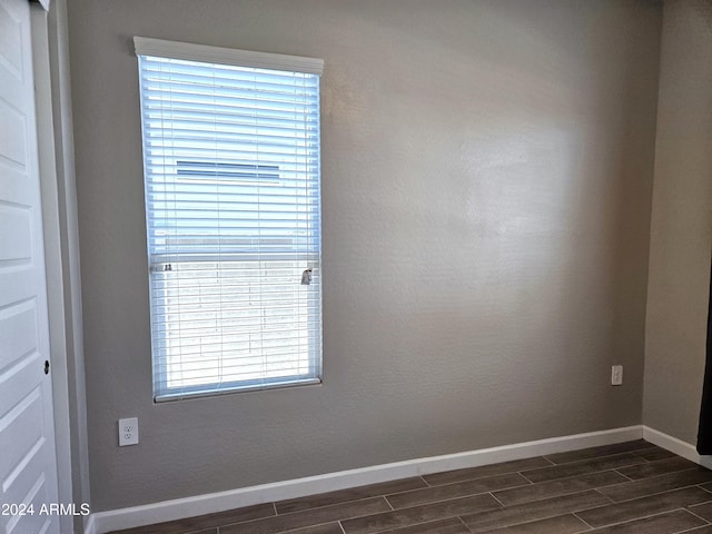 empty room with dark wood-type flooring and a wealth of natural light