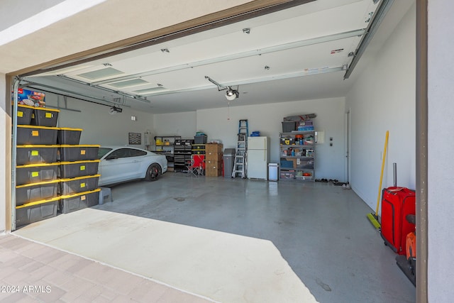 garage featuring white fridge and a garage door opener