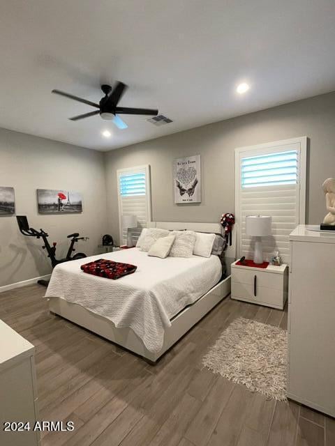 bedroom with ceiling fan, multiple windows, and wood-type flooring