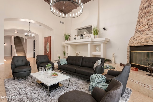 tiled living room with a notable chandelier, a towering ceiling, and a fireplace