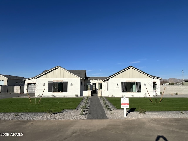 modern inspired farmhouse with board and batten siding, an attached garage, a front yard, and fence