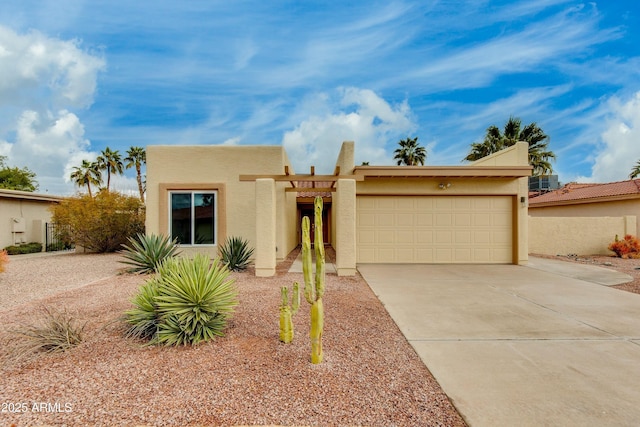 pueblo revival-style home with stucco siding, concrete driveway, and an attached garage