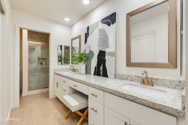 full bathroom featuring double vanity, a stall shower, and a sink