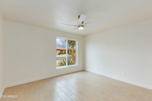 spare room with baseboards, light wood-style floors, and ceiling fan