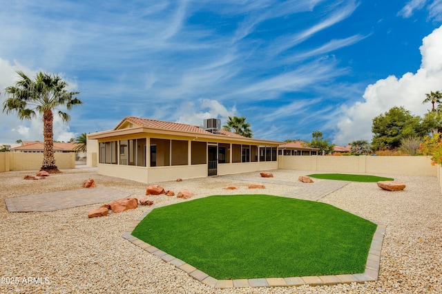 rear view of property with a fenced backyard, a patio, and a sunroom