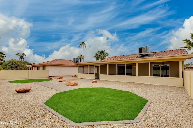 rear view of property featuring a patio, a fenced backyard, a sunroom, central air condition unit, and a tiled roof