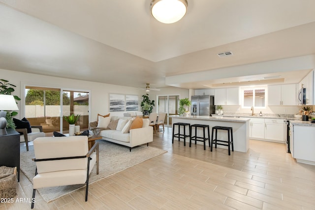 living room with visible vents, a ceiling fan, and wood tiled floor