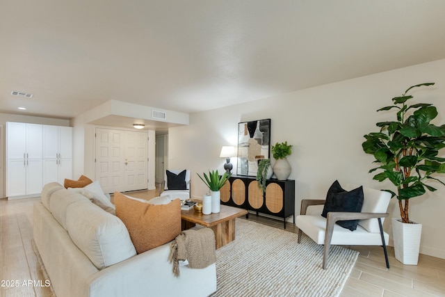 living area featuring light wood-style flooring and visible vents