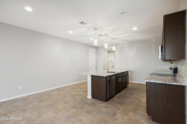 kitchen featuring light stone countertops, sink, hanging light fixtures, stainless steel appliances, and a kitchen island with sink