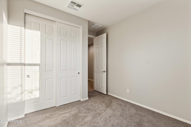 unfurnished bedroom with light colored carpet and a closet