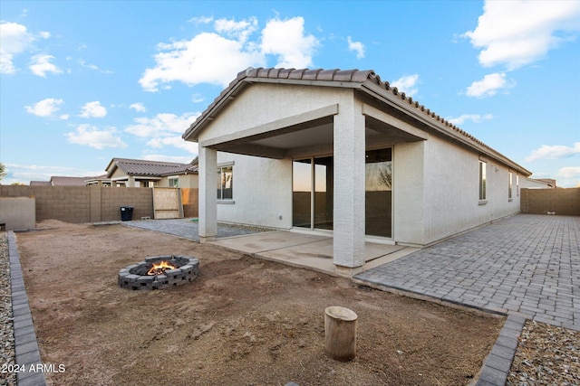 rear view of property with a patio area and an outdoor fire pit