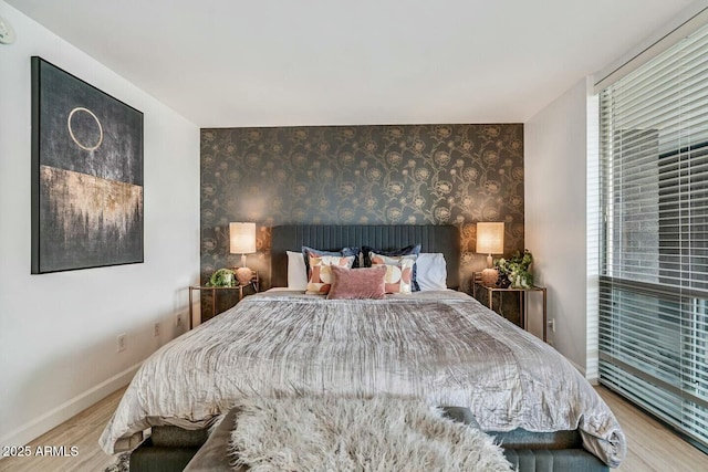 bedroom featuring baseboards, wood finished floors, and wallpapered walls