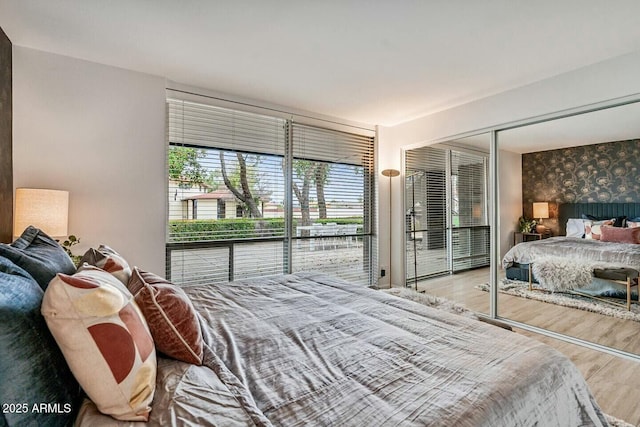 bedroom featuring wallpapered walls, an accent wall, and wood finished floors