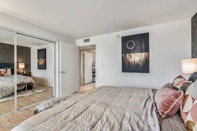 bedroom featuring a closet, visible vents, and wood finished floors