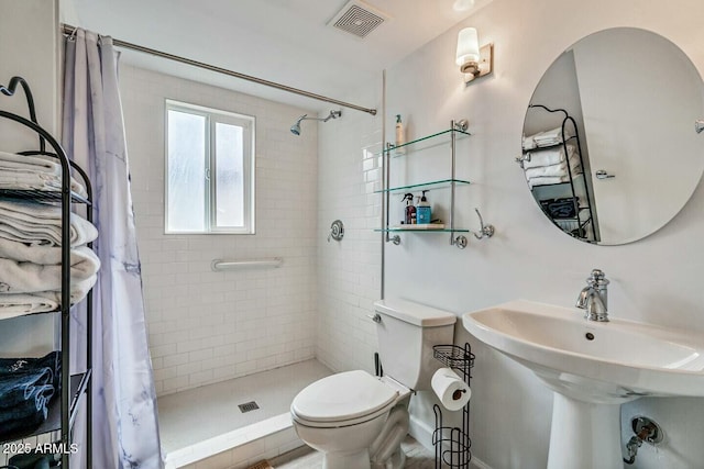 full bathroom with visible vents, a tile shower, a sink, and toilet