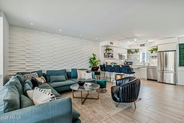 living room with light wood-type flooring, rail lighting, visible vents, and recessed lighting