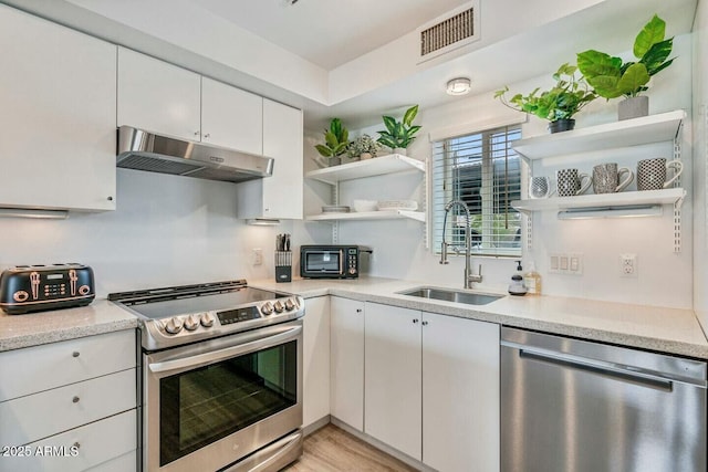 kitchen featuring appliances with stainless steel finishes, a sink, under cabinet range hood, and open shelves