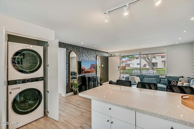 kitchen featuring light stone countertops, stacked washing maching and dryer, open floor plan, and recessed lighting