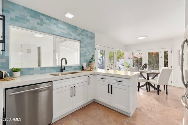 kitchen with sink, french doors, stainless steel dishwasher, backsplash, and white cabinets