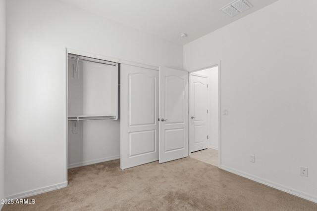 unfurnished bedroom featuring light carpet and a closet