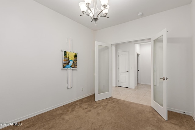 carpeted empty room featuring a notable chandelier and french doors