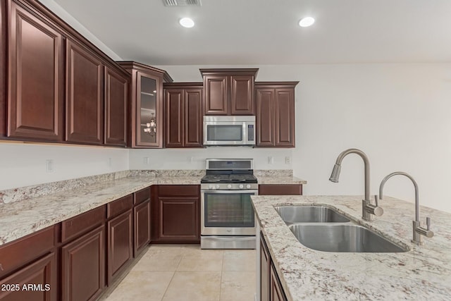 kitchen featuring stainless steel appliances, sink, light tile patterned floors, and light stone counters