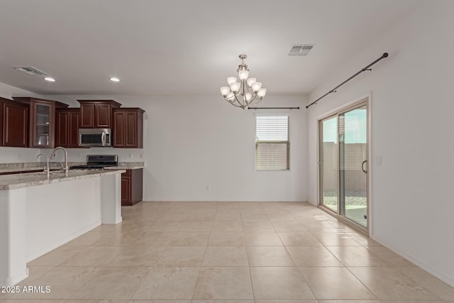 kitchen with light stone counters, stainless steel appliances, dark brown cabinets, and light tile patterned floors