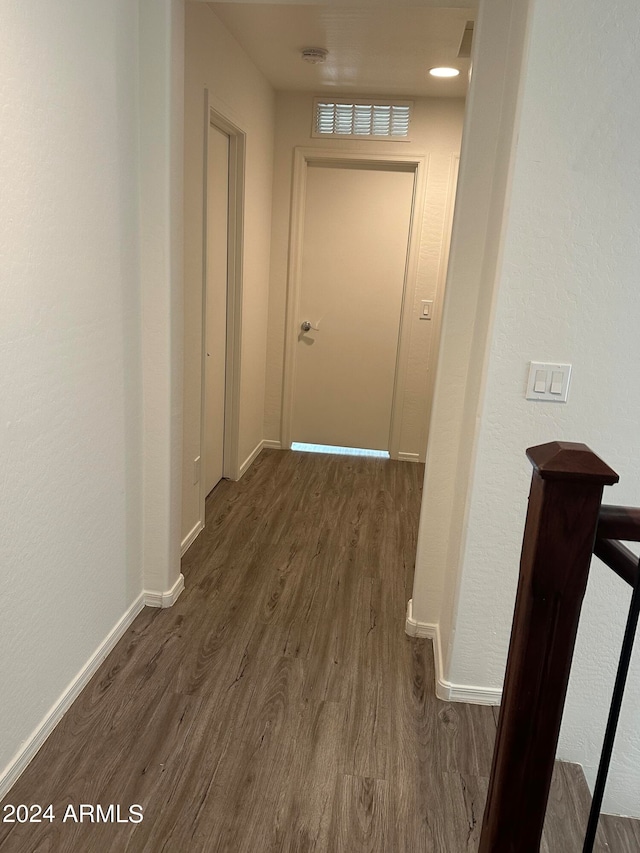 hall with dark wood-style floors, visible vents, and baseboards