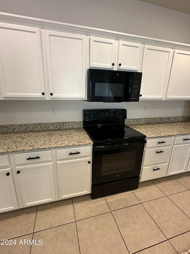 kitchen featuring black appliances, light stone counters, light tile patterned flooring, and white cabinetry