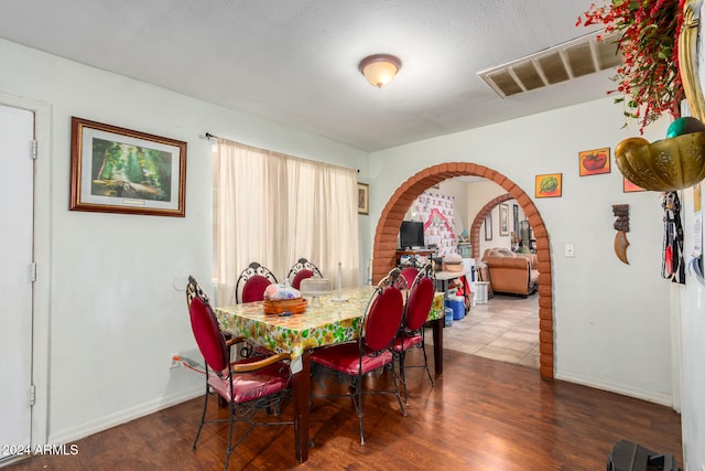 dining space with dark wood-type flooring and a textured ceiling