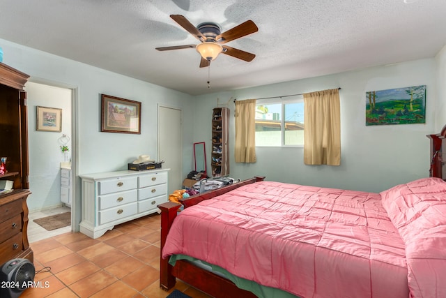 tiled bedroom featuring ensuite bathroom, ceiling fan, and a textured ceiling