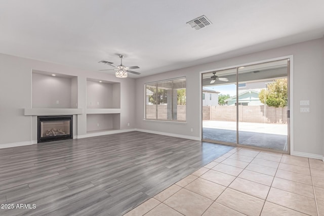 unfurnished living room featuring visible vents, ceiling fan, and a wealth of natural light