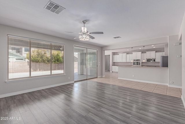 unfurnished living room featuring a ceiling fan, baseboards, visible vents, and light wood-style floors