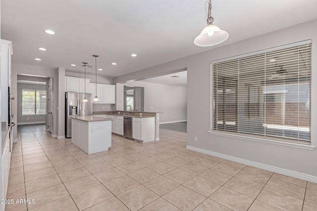 kitchen featuring a peninsula, a kitchen island, white cabinetry, appliances with stainless steel finishes, and light tile patterned floors