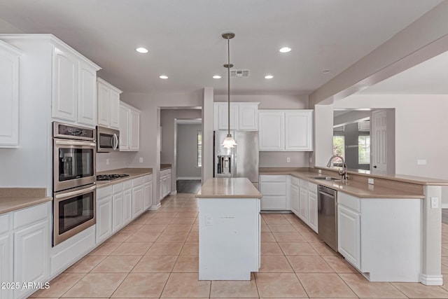 kitchen featuring visible vents, a kitchen island, recessed lighting, a sink, and stainless steel appliances