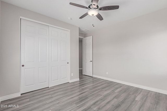 unfurnished bedroom with ceiling fan, baseboards, light wood-type flooring, visible vents, and a closet