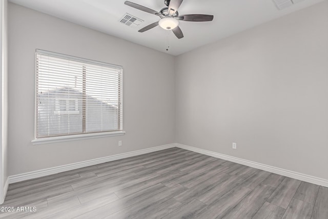 spare room featuring baseboards, ceiling fan, visible vents, and wood finished floors
