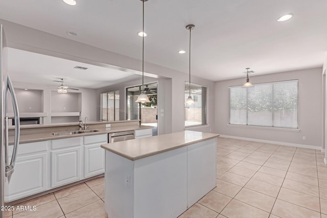 kitchen with a kitchen island, light tile patterned flooring, ceiling fan, white cabinets, and a sink