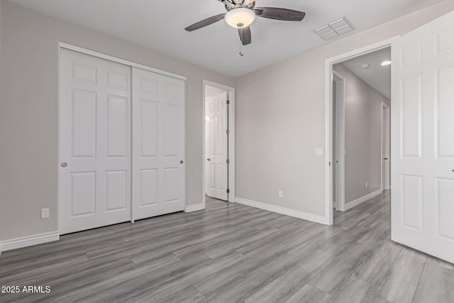 unfurnished bedroom with a ceiling fan, baseboards, wood finished floors, visible vents, and a closet