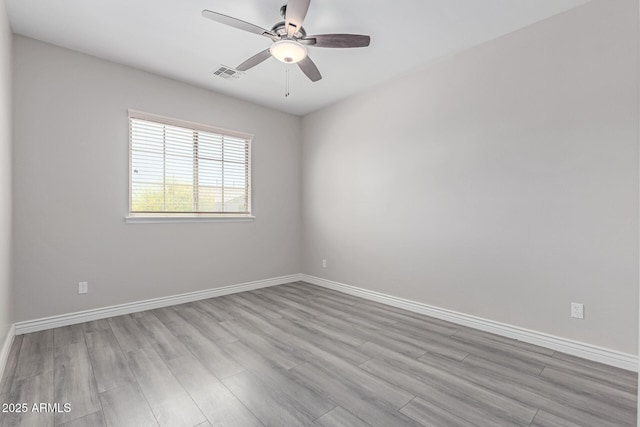 spare room featuring baseboards, a ceiling fan, wood finished floors, and visible vents