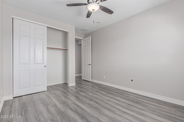 unfurnished bedroom featuring baseboards, a closet, wood finished floors, and visible vents