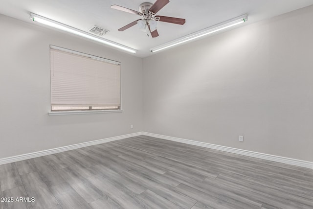 spare room featuring visible vents, baseboards, ceiling fan, and wood finished floors